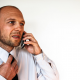 A man in a shirt and tie talks on the telephone for a job interview