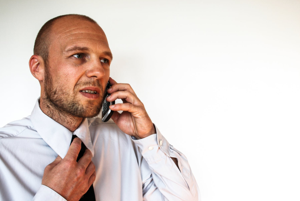 A man in a shirt and tie talks on the telephone for a job interview