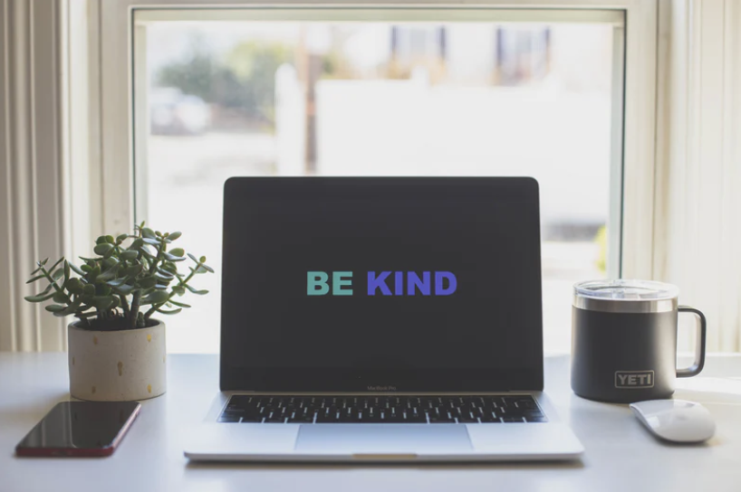 A computer has the words 'be kind' showing on it
