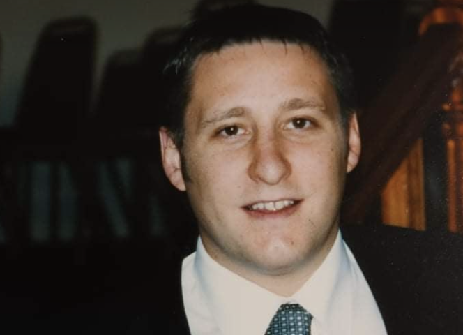 Anthony McCormack wearing a white shirt, blue tie and black suit